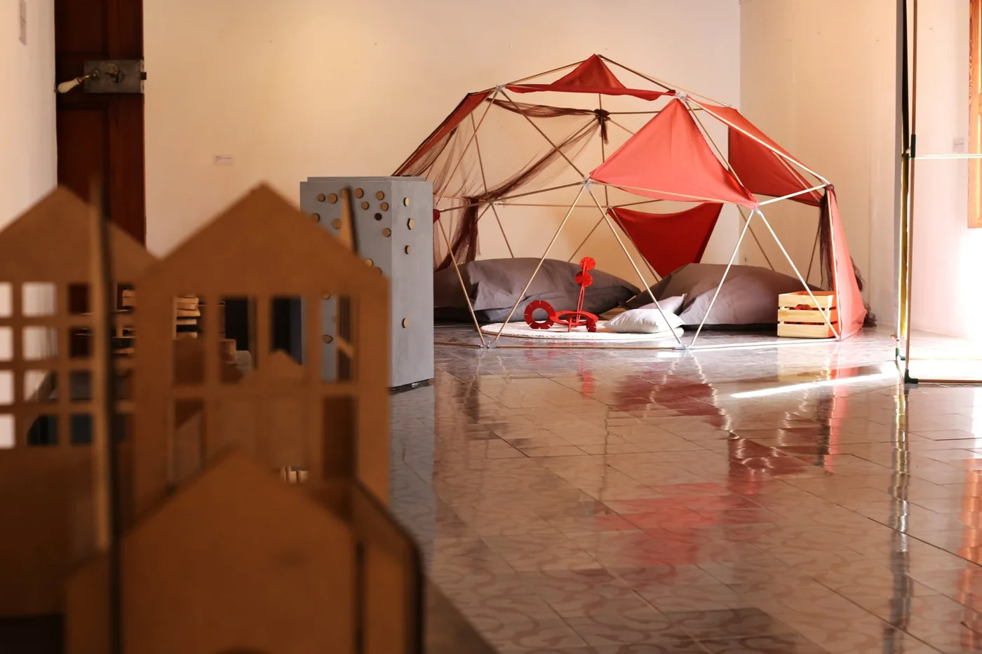 Refuges en bois et structure géométrique rouge dans un espace de jeu à Can Prunera